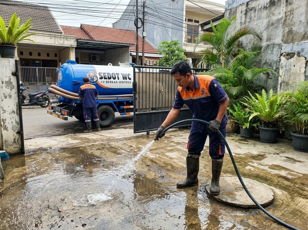 Teknisi menyemprot dan membersihkan halaman setelah pengurasan septic tank.