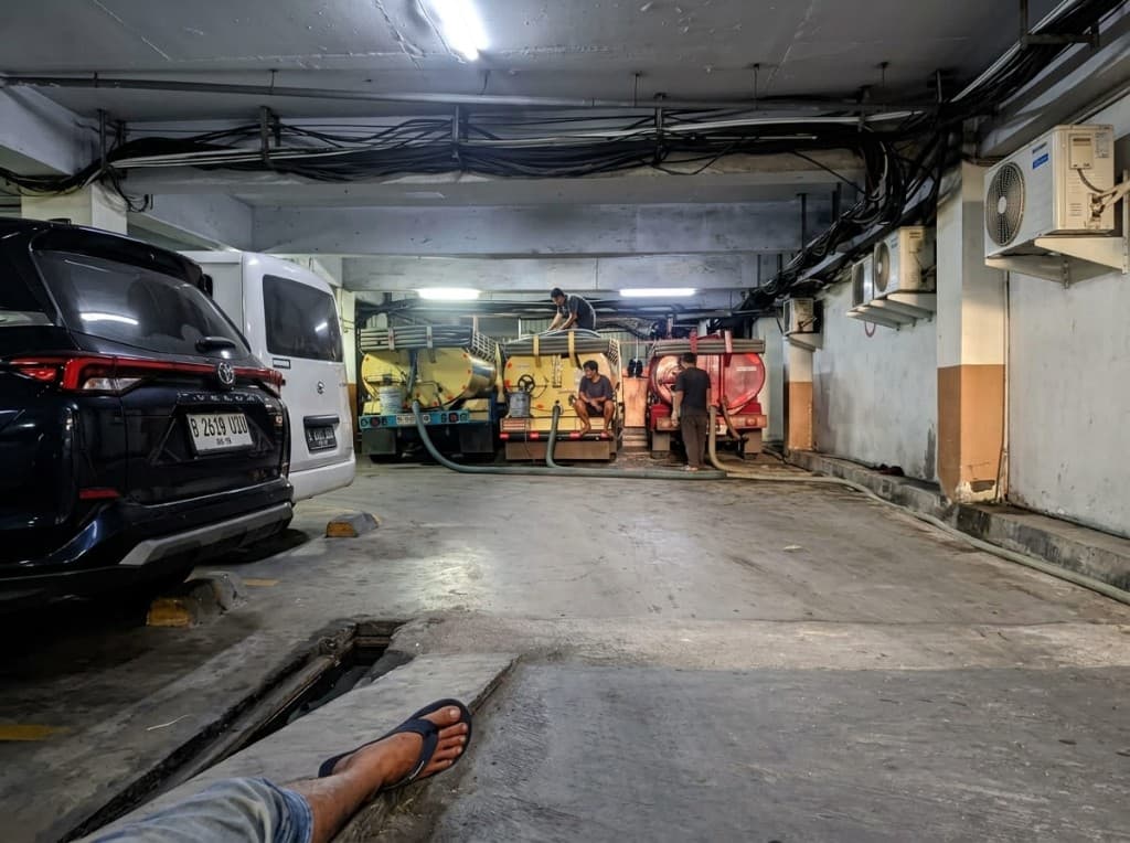 Pengerjaan sedot di basement gedung, dua unit tangki di area parkir.